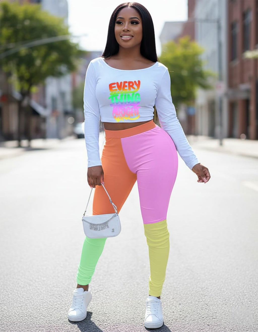 Woman wearing a colorful outfit with a white long-sleeve crop top and multicolored leggings on a city street.