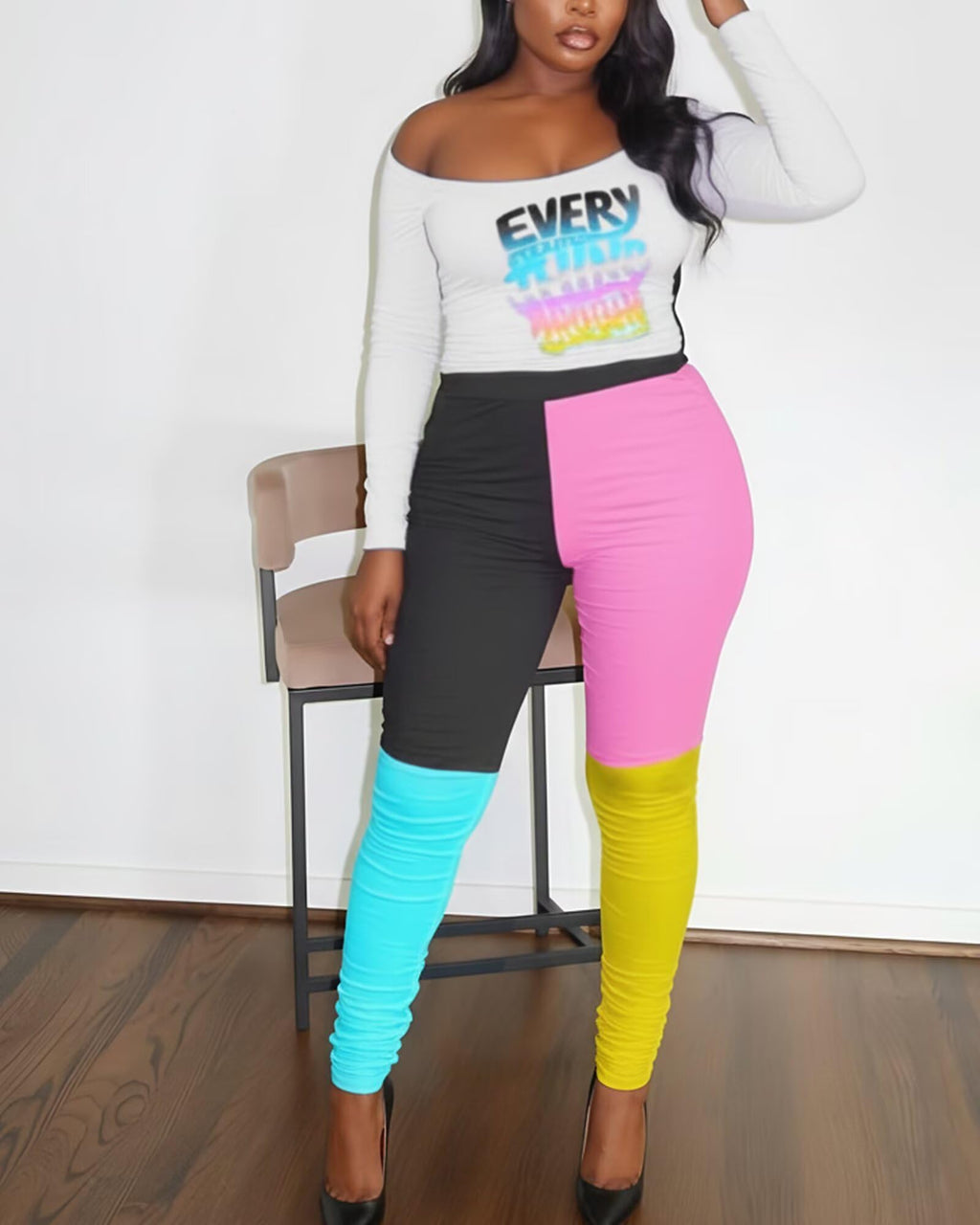 Person wearing a white long-sleeve top with colorful text and multicolored leggings.